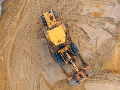 黄色挖掘机或推土机在施工现场使用沙子鸟瞰或俯视图进行工程