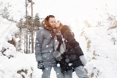 一对年轻的夫妇, 一个男人和一个女人在冰雪覆盖的森林里散步。冬季休闲。一起旅行。爱会在任何霜冻中温暖