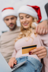有选择的焦点在圣诞老人帽子购物在线与信用卡和笔记本电脑在家