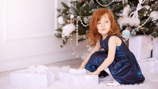 小女孩。 白色背景。 蓝色连衣裙。 新年圣诞节的孩子。 平安夜假期。 内部。 礼物。