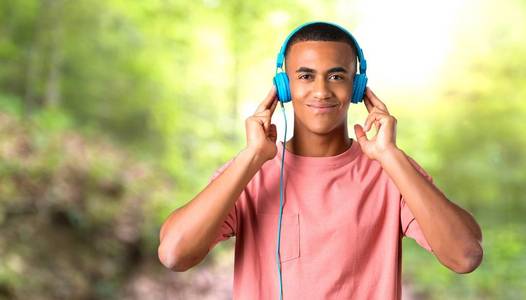 年轻的非裔美国人带着耳机在公园里听音乐