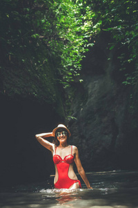 在丛林河里的年轻的旅行妇女。巴厘岛雨林。旅游探险概念