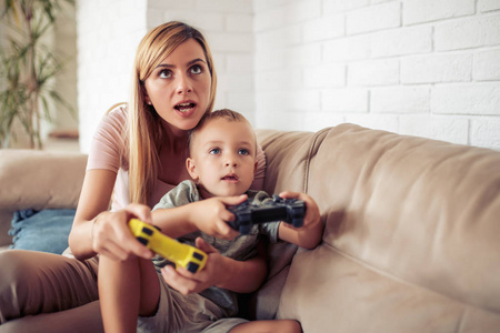 快乐的年轻妈妈和儿子一起玩电子游戏。