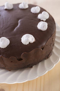 木制背景的白色盘子上装饰着白色奶油的巧克力蛋糕