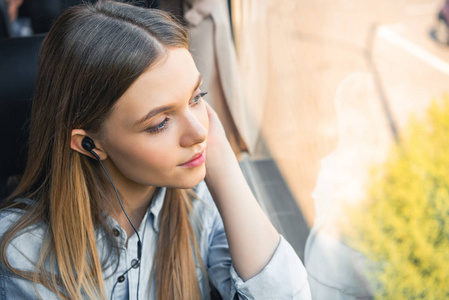 女旅客在公共汽车旅行时，在耳机中选择性地收听音乐