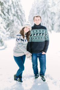 一对年轻夫妇一起在白雪皑皑的冬天森林里散步，一起度过圣诞假期