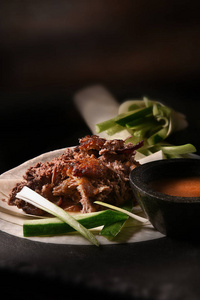 创造性地点燃了肉质经典的中国肉丝北京烤鸭与海辛酱和面粉煎饼与葱片和黄瓜装饰。复制空间。