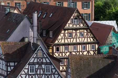 在六月的一个阳光明媚的日子里，在德国南部的一个历史城市的中心，你可以看到屋顶和木框架的建筑，房子旁边有绿色和树木