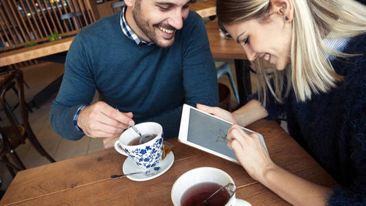 年轻有魅力的夫妇在咖啡店里用数码平板电脑