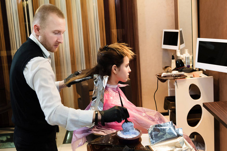 s hair, gloves on his hands, a concentrated look. Hair stylist c