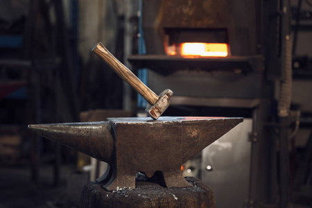 金属加工车间或铁匠铺红热炉前铁砧上的木槌