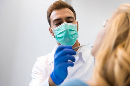 年轻牙医戴口罩检查女性客户牙齿的底视图