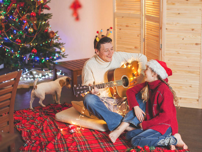 女孩与爸爸演奏吉他和唱歌在圣诞节附近 tr
