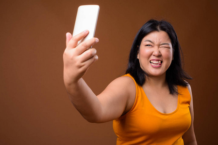 美丽的超重亚洲妇女使用手机采取自拍