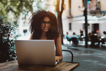  smiling caucasian female with curly hair using the netbook whil