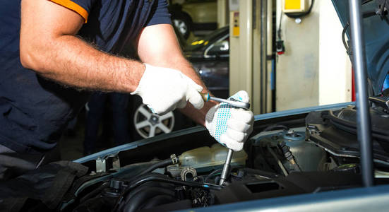 汽车机械师的手与扳手在汽车修理服务。