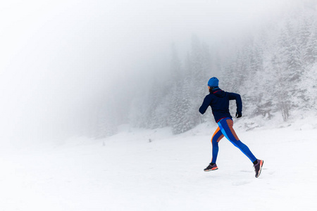 在冬天的山上和森林里，女人在雪地上奔跑。 运动健身的灵感和动力。 年轻快乐的女孩运动员在下雪的冬天工作。 女跑步者在户外慢跑。