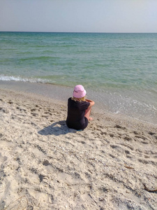 坐在海滩上的粉红色巴拿马的妇女
