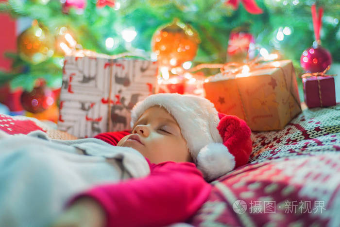 可爱的小女婴睡在圣诞树附近