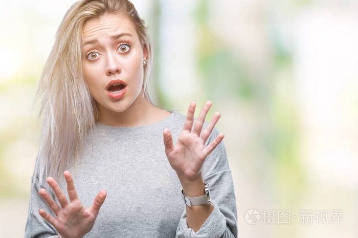 年轻的金发女人在孤立的背景下害怕和恐惧,表情停止手势,双手震惊地