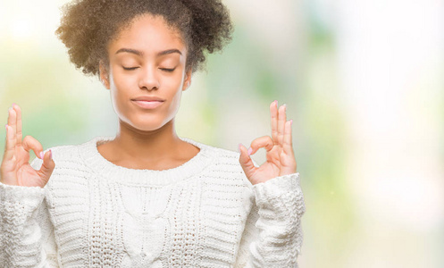 年轻的美国黑人妇女穿着冬天的毛衣，在的背景下放松和微笑，闭着眼睛做冥想手势用手指。瑜伽概念。
