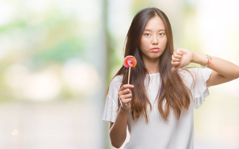 年轻的亚洲妇女在孤立的背景下吃棒棒糖