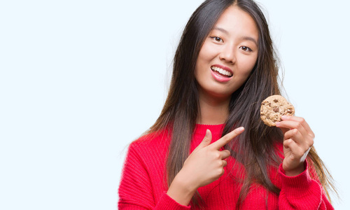 年轻的亚洲女人吃巧克力片饼干的背景