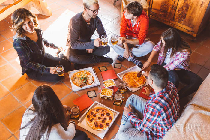 一群年轻人玩着吃比萨饼和喝啤酒,青少年朋友一起参加聚会和庆祝