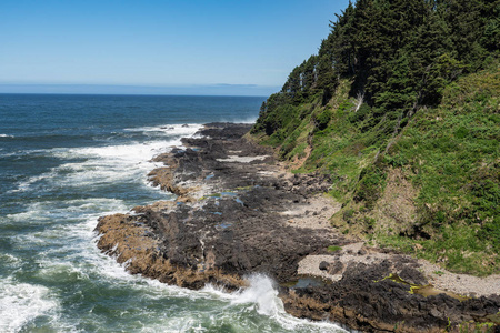 波浪沿着俄勒冈州海岸海滩太平洋破碎，充满了岩石和石头。暑假就要放假了。