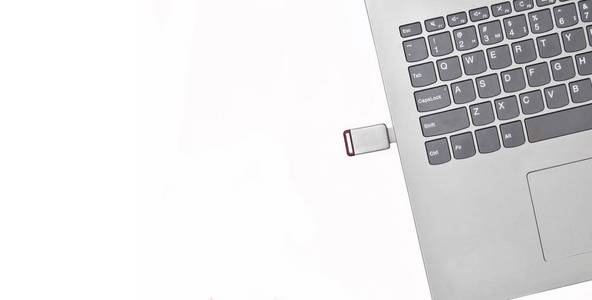 USB闪存驱动器插入笔记本电脑隔离在白色背景。 现代数字媒体。