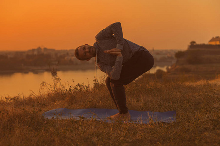 在日落时做瑜伽的人，以城市的视角旋转椅子姿势Parivrttautkatasana.色调的图像。