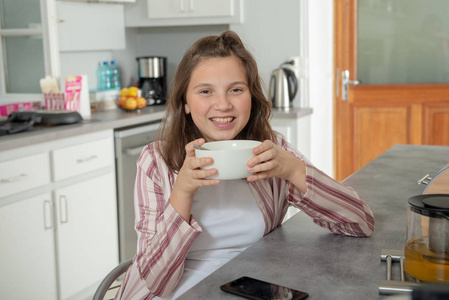 一个十几岁的女孩在碗里喝咖啡
