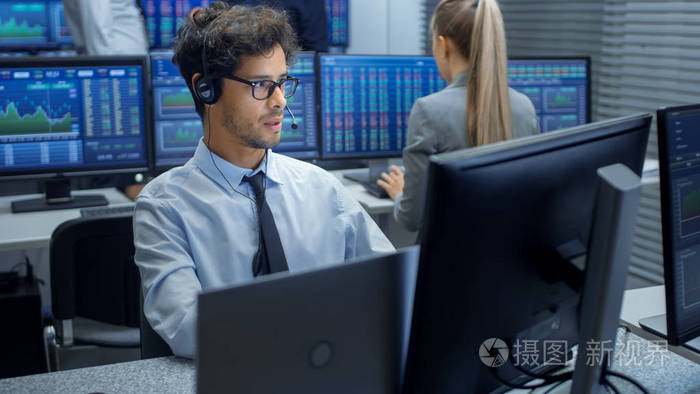 股票交易员用耳机进行销售在后台证券交易所办公室和一群交易员在他们