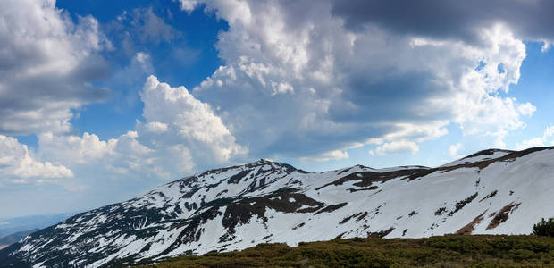 山高山高的全景，顶部覆盖着雪，一片绿草如茵的草坪。旅游休息地，喀尔巴阡山脉，乔诺霍拉山脉。