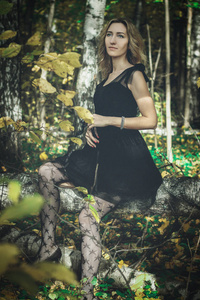 一个年轻的女巫，穿着黑色衣服，戴着黑色面具，在神秘的森林里摆出各种姿势。 艺术加工。