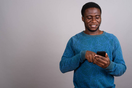 年轻的非洲男子在灰色背景下使用手机