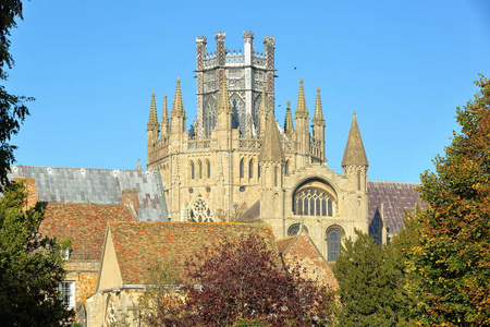 靠近位于英国剑桥郡诺福克的爱丽大教堂的炮塔尖和八角形，前景和秋天的颜色是中世纪的屋顶