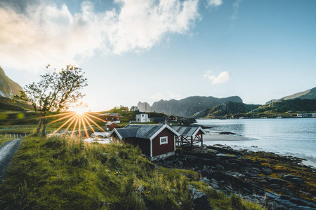 传统的红色钓鱼房子在 Bjoernsand 附近的女王, 挪威与红色弗洛罗的房子。日落午后与云彩在沙滩上