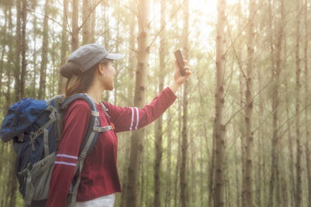 时髦的游客在旅行生活方式概念冒险旅行者上拍照，背包在背景森林景观地平线上，年轻女孩徒步旅行者指着徒步旅行计划。