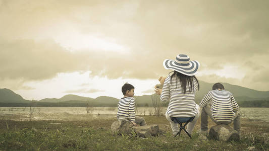 妈妈和儿子在湖边野餐。亚洲家庭。