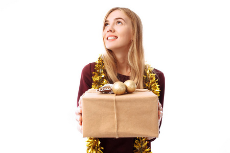 忧郁的年轻女人戴着圣诞老人的帽子，梦想着在她的手中寻找一个白色背景上的礼品盒。 圣诞节