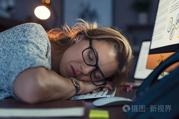 特写脸疲惫的女商人加班睡觉. 黑暗办公室里金发困倦女人的肖像.