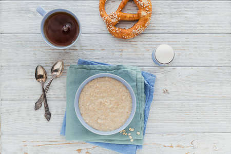 燕麦粥碗里放着红茶，面包和煮鸡蛋放在白色的木质背景上..健康的营养早餐。健康饮食，节食的理念..提供免费文本空间的俯视图