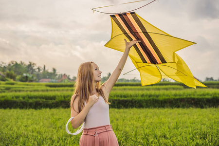 印度尼西亚乌布巴利岛绿色稻田里放风筝的年轻妇女。