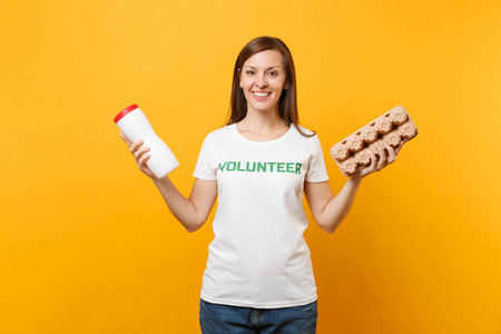 妇女肖像白色T恤与书面铭文绿色标题志愿者持有塑料瓶纸板箱隔离在黄色背景。 自愿免费援助帮助垃圾分类概念