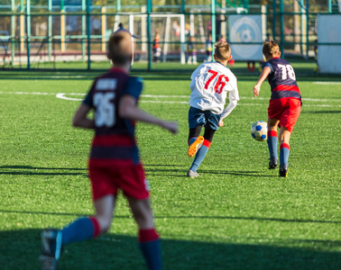 足球队的男孩穿着红色蓝色白色运动服在绿色的球场上踢足球。 孩子们运球。 运球技巧。 团队游戏训练活动生活方式爱好运动儿童概念