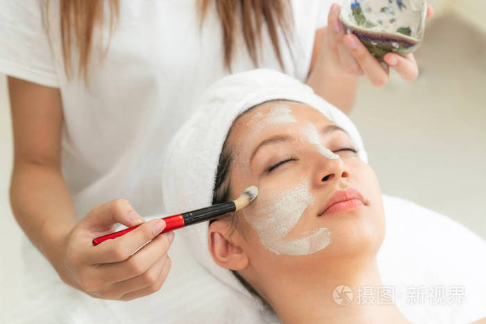 美丽的女人有一个面部美容擦洗治疗从专业皮肤科医生在健康水疗.