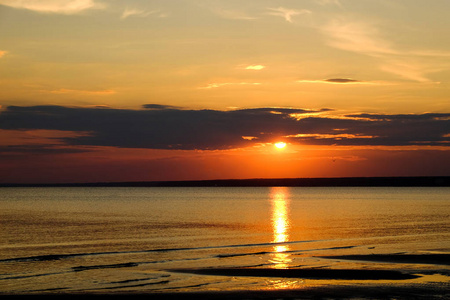 夕阳在海上和橙色的天空上美丽的炽烈的景色，在背景中平静的波浪上，太阳的金色反射令人惊叹。 海滩上令人惊叹的夏季日落景色。