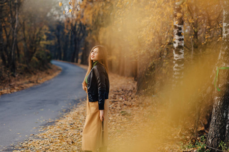 舒适时尚的年轻女孩独自走在秋天五彩缤纷的公园里