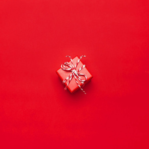 一个红色礼品盒与装饰花边的红色背景顶部视图平躺。 节日概念新年或圣诞礼品盒赠送圣诞假期。 祝贺背景与文本空间